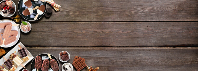 Fototapeta na wymiar Cool summer food corner border. Various chocolate theme ice cream and frozen treats. Overhead view on a dark wood banner background. Copy space.