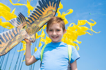 a happy boy holds in his hand a flying kite with a picture of a bird, a joyful child at the...