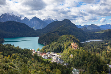 Fototapeta na wymiar Castle on a mountain backdropped by a lake and Alps