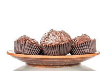 Four homemade chocolate muffins on a clay plate, macro, isolated on white background.