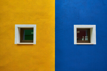 colorful house facade on Burano island, north Italy. Half orange half blue house wall with a yellow...