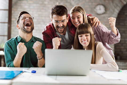 Cheerful entrepreneurs celebrating their success while using computer in the office