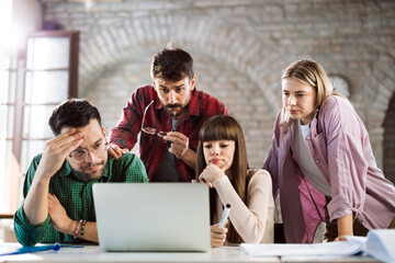 Fototapeta premium Young freelance workers having problems while working on laptop in the office