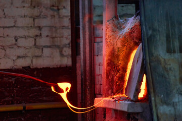 Murano glass-blowing factory. blower forming beautiful piece of glass: put iron rod with attached glass object in furnace to make the glass malleable - obrazy, fototapety, plakaty