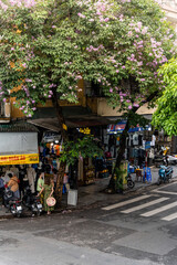 Obraz premium People, vendors, bicycles and cyclo drivers taking tourist on a busy, bustling street in the old town of Hanoi, in northern Vietnam. Famous destination of Vietnam
