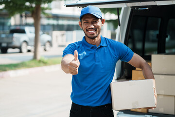 Happy Asian delivery man holding a box package and showing thumbs up.