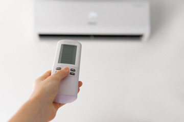 hand with air conditioner remote control. turning on the air conditioner close-up with a blurred background. climate control.