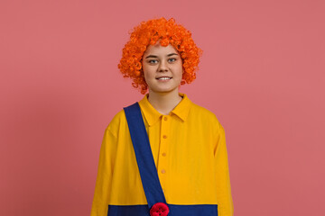 smiling girl in a wig and a clown costume on a colored background