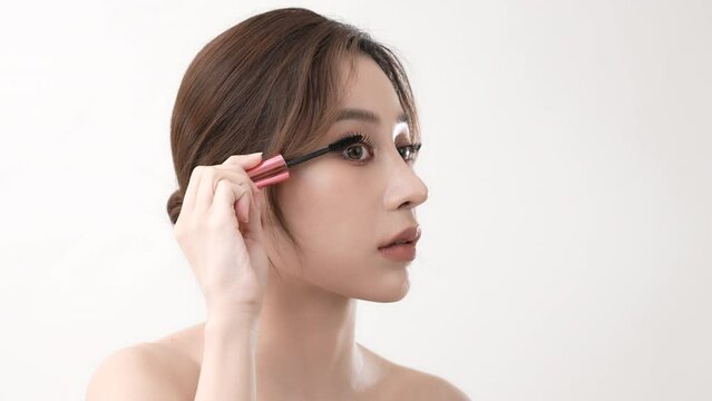 Beauty concept of 4k Resolution. Asian woman brushing eyelashes on a white background.