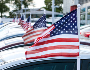 American flags on cars at automobile dealership.