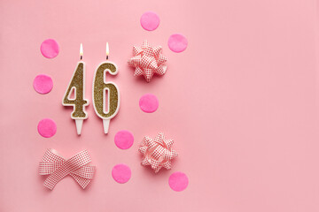 Number 46 on pastel pink background with festive decor. Happy birthday candles. The concept of celebrating a birthday, anniversary, important date, holiday. Copy space. Banner