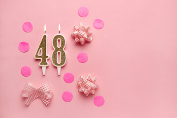 Number 48 on pastel pink background with festive decor. Happy birthday candles. The concept of celebrating a birthday, anniversary, important date, holiday. Copy space. Banner