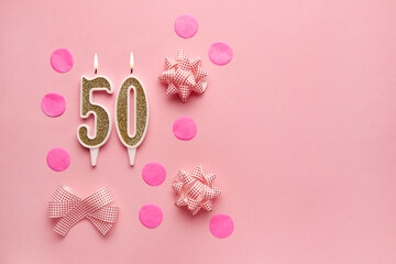 Number 50 on pastel pink background with festive decor. Happy birthday candles. The concept of celebrating a birthday, anniversary, important date, holiday. Copy space. Banner