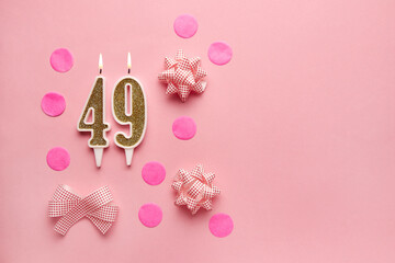 Number 49 on pastel pink background with festive decor. Happy birthday candles. The concept of celebrating a birthday, anniversary, important date, holiday. Copy space. Banner