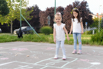 Two little girls playing hopscotch ,We love to play together
