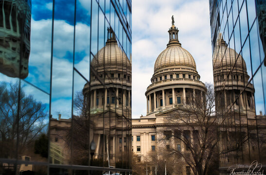 state capitol domes reflected in reflection of tall buildings