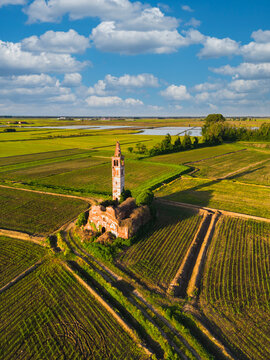 Aerial view of abandoned church in the middle of the wheat fields with rise fields in background. Novara, Piedmont