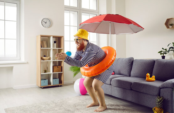 Funny fat man being at home going on summer vacation and imagining how he dives into sea. Side view of chubby man in striped swimsuit and with inflatable circle at waist imitates diving in living room