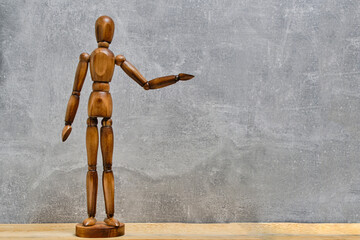 Wooden mannequin stands with an outstretched arm gray background.Concept offering and begging.