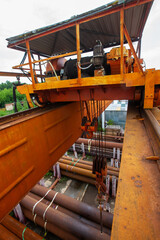 Overhead crane boom and hook from top to bottom closeup. Rusted pipes down