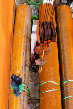Worker, rusted tubes and crane hook