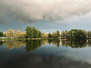 Trees reflection on the pond surface, park, lake in the park, cloudy sky