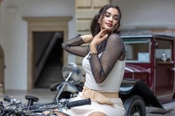 Fototapeta na wymiar Young woman with long black hair is sitting seductively on a vintage motorcycle. Horizontally. 