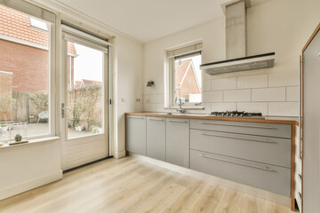 a kitchen with wood flooring and white tile on the walls, in front of an open window looking out onto a brick wall