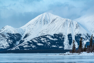 Incredible snow capped mountains in the winter time with a frozen lake in foreground. Taken in Atlin, British Columbia near Alaska, Yukon Territory, Canada. 