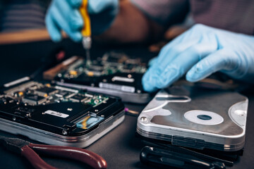 Obraz premium Computer service engineer technician workplace repairing fixing disassembled HDD hard drive data disc SSD, backup part of PC or laptop. Recovery, maintenance work, access file. Profession repairman