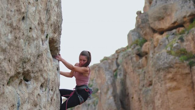 The girl climbs the rocks, rock climbing in nature. sports girl is engaged in rock climbing. extreme sport