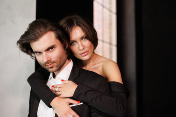 Gorgeous beautiful woman with a man touching each other. A lovely couple dressed in evening clothes. Wife and husband embrace and kiss passionately