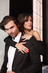 Gorgeous beautiful woman with a man touching each other. A lovely couple dressed in evening clothes. Wife and husband embrace and kiss passionately