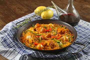 Valencian paella with porrenes of red wine on the wooden table