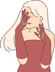 Elegant woman in evening dress covers face with hands, wanting to show off gold rings and jewelry