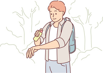 Man uses anti-mosquito spray while walking in forest or natural park in summer weather