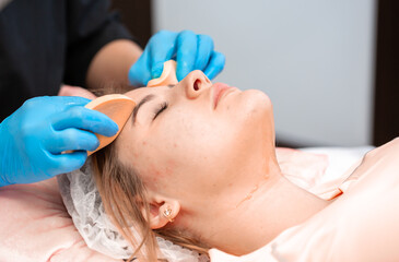 The girl at the beautician makes spa treatments, massage, facial cleansing and a mask for the skin. Cosmetic procedures in a beauty salon, facial skin care for rejuvenation.