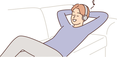 Man listens to music lying on couch with headphones and enjoys cool audio sound of favorite track