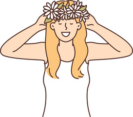 Woman puts on head wreath of spring flowers collected in meadow and rejoices at onset warm weather