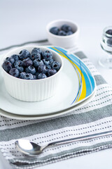 Fresh Blueberries in a bowl on white plates on a table fabric
