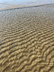 Transparent sea water and sandy bottom, ripples on the sea water, natural sea water background