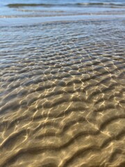 Transparent sea water and sandy bottom, ripples on the sea water, natural sea water background