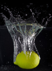 Fototapeta na wymiar Fresh lemon falling into the water with a splash of water on a black background