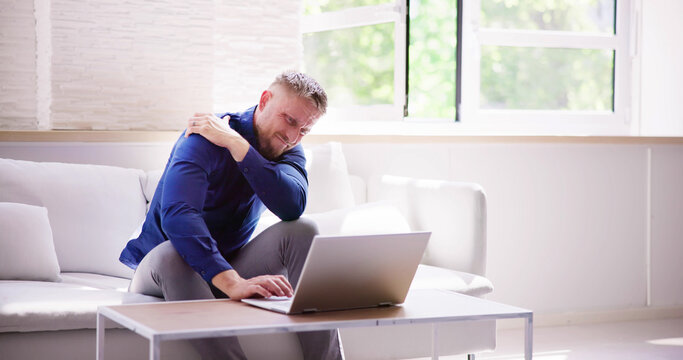 Man Working On Laptop Computer With Shoulder Injury Pain