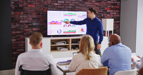 Businesspeople Looking At Businessman Giving Presentation