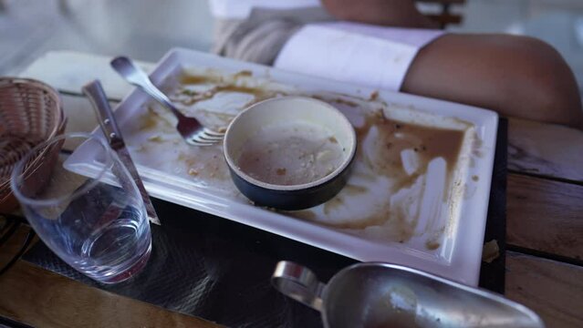 Empty dish with fork after eating on a wooden table. Top view of empty plate dirty after the meal is finished at restaurant