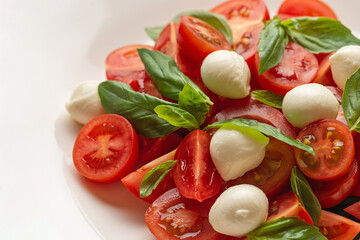Salad with cherry tomatoes and mozzarella in a white plate on a gray background