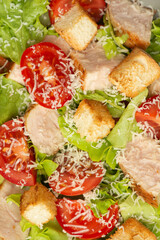 Vegetable salad with chicken and cheese on a gray table. Caesar salad in a gray plate.