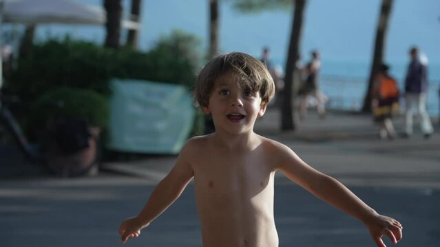 One joyful little boy standing outside during beautiful summer day. Small male shirtless child enjoying holidays