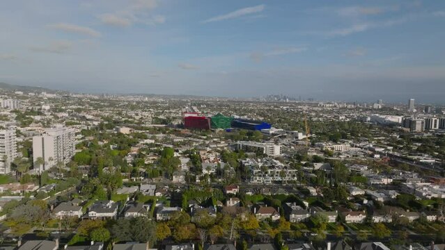 Fly above residential district in large city. Rows of houses along streets. Significant colour building of Pacific Design Center.